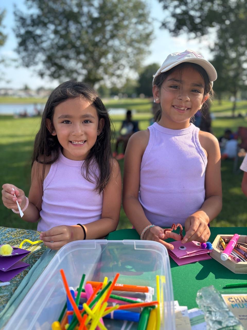 Two smiling friends crafting at a park pop-up