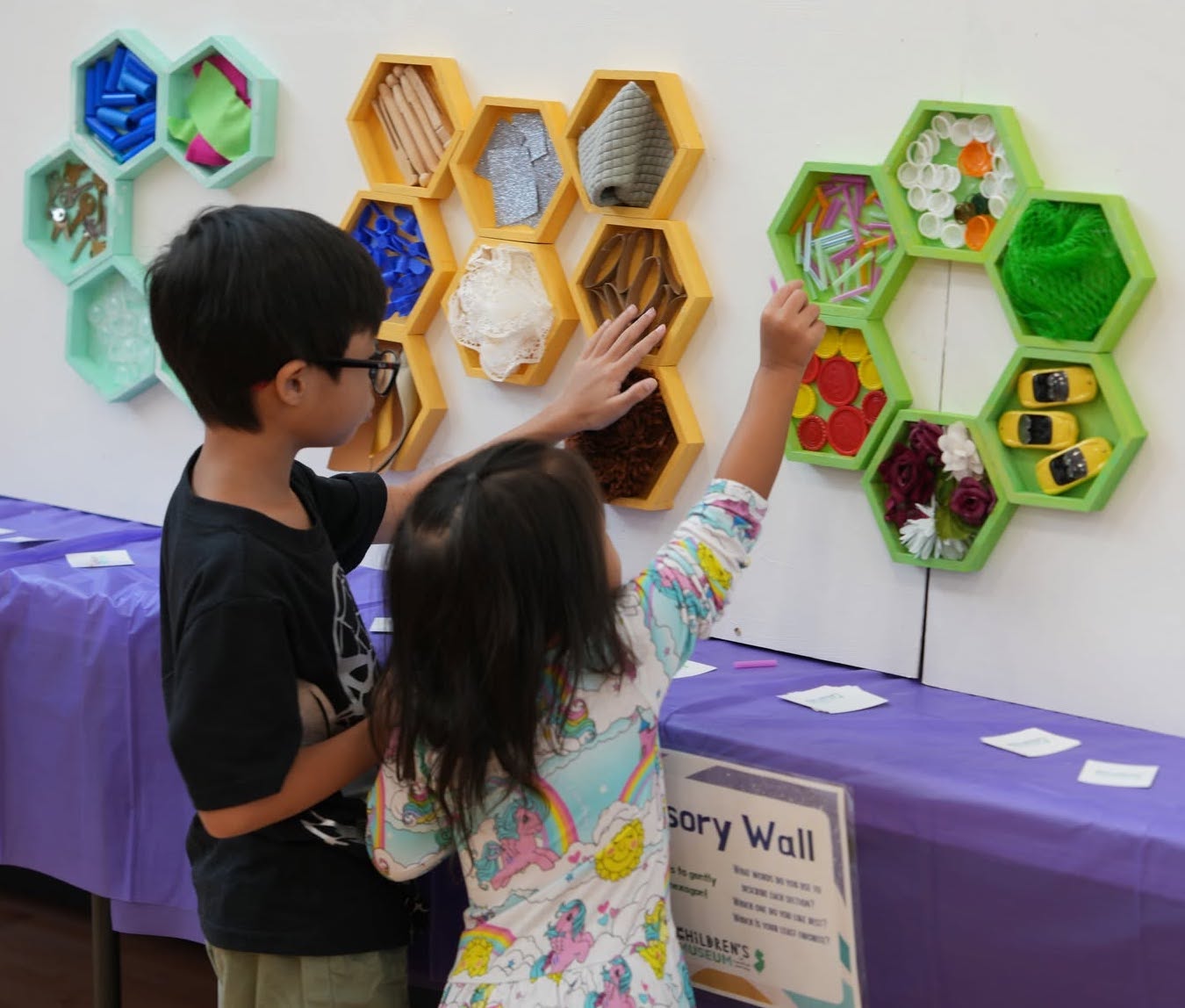 Children exploring a colorful hexagon sensory wall at a CMOCJ pop-up